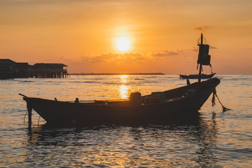 Wooden fishery boat floting on the sea with sunset time.