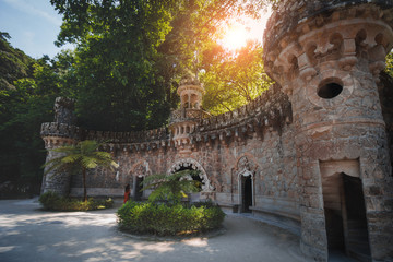 Romantic girl in a red dress is walking in the Regaleira Palace (Quinta da Regaleira) and a...