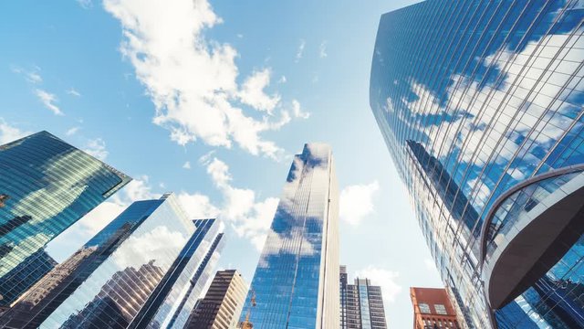 4K UHD time-lapse of buildings in business district, fast moving cloud on sunny day sky, zoom out then still. Financial economy, construction industry, or internet communication technology concept