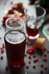 pomegranate juice in a glass Cup and a bottle with fresh pomegranates and grains