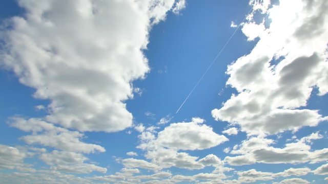 Airplane flying in the blue sky among clouds and sunlight