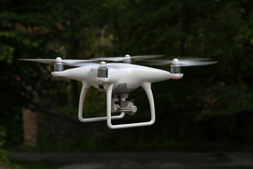 Flying quadcopter with digital camera on blurred background