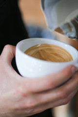 cup of coffee in hands of man on a background, barista preparing cappuccino