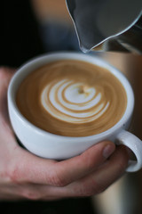 cup of coffee in hands of man on a background, barista preparing cappuccino