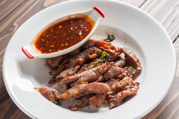 Charcoal-boiled pork neck and sauce on a wooden floor .Grilled Pork thailand style