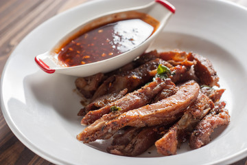 Charcoal-boiled pork neck and sauce on a wooden floor .Grilled Pork thailand style