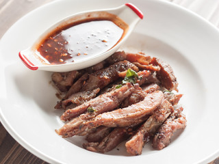 Charcoal-boiled pork neck and sauce on a wooden floor .Grilled Pork thailand style