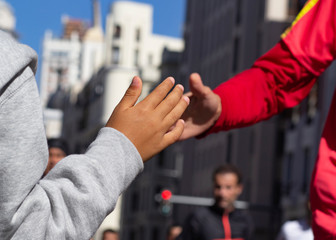 Child's hand crashing with runner’s hand cheering his effort, closeup with background defuse