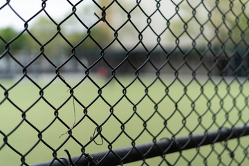 Fototapeta premium Chain link fence in a park, blurry background