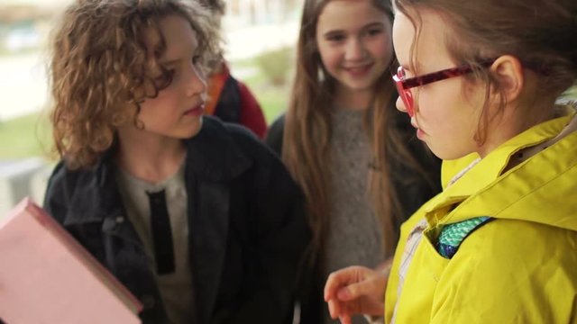 Children are pushing a girl, screaming in her face, breaking glasses. Bulling at school teenagers. The brutal behavior of students. A group of teenagers offend and insult a classmate. Close up