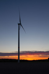 Wind turbine during blue hour with dramatic sunset on the horizon