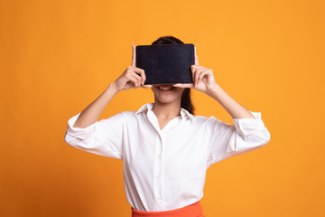 Young Asian woman with a computer tablet over her face.