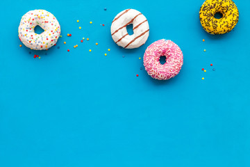 Donuts of different flavors for breakfast on blue background top view