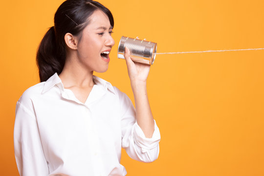 Young Asian woman shout with tin can phone.
