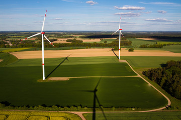 Two wind turbines with long shadows in the evening from a birds eye view
