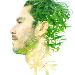 Double exposure of a young handsome man’s portrait blended with bright green leaves, showing the...