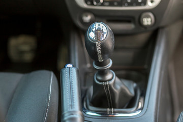 Luxurious car black leather interior. Close-up detail of handbrake manual brake and gearshift stick on blurred dashboard background. Transportation, design, modern technology concept.