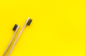 Eco materials concept with bamboo tooth brush on yellow background top view copy space
