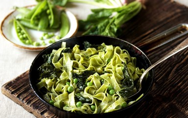 green fettuccine pasta with spinach leaves and green peas. ready meals, vegetarian cuisine. Italian food.