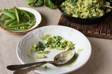 the process of eating pasta fettuccine with spinach leaves and green peas. Dirty dishes. vegetarian cuisine. Italian food.