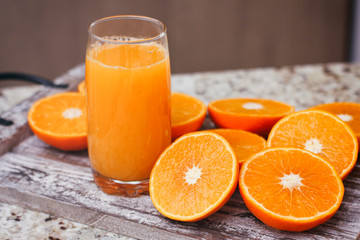 Fresh orange juice in clear glass. Sliced citrus on wooden table.
