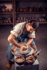 Charming potter female student shows how to work with clay and pottery wheel. Handwork.