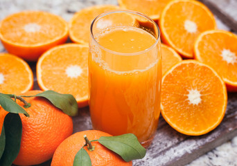 Fresh orange juice in clear glass. Sliced citrus on wooden table.