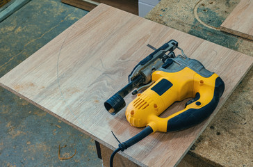 Electric jig saw cuts the workpiece from chipboard for furniture
