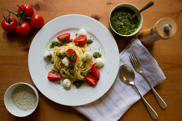 Topview of a tasty dish with Spaghetti, pesto genovese, tomatoes and mozzarella