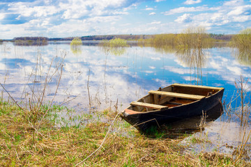 Old wooden boat near the river. Spring flood