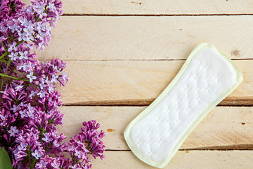 lilac branch and female pads on wooden background. the view from the top