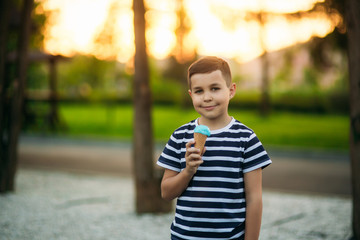 A little boy in a striped T-shirt is eating blue ice cream.Spring, sunny weather