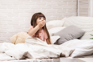 cute little child girl wakes up from sleep in bed in the morning