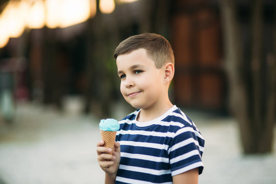 A Little Boy In A Striped T-shirt Is Eating Blue Ice Cream.Spring, Sunny Weather