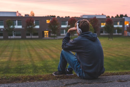 Upset teenager sitting on the ground all alone while listening to some music.