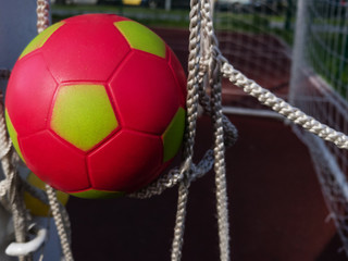 Red with yellow kids soccer ball in the football goal net as a symbol of the great victory of the team of young players. close up