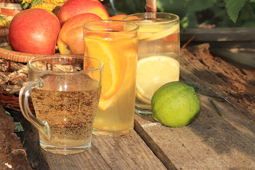 Summer drinks in the garden on an old table with dandelions. Apple and lemon juices on an old...