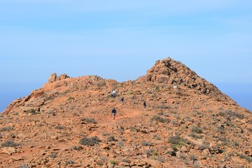 Tourists on one of the tops of hills with red soil. Part of the wild landscape of the south-west part of Fuerteventura. Fuerteventura mountains