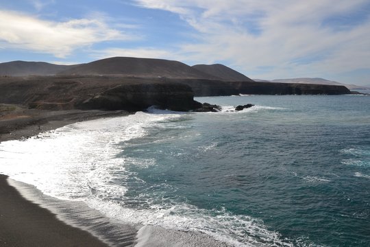 Black sand volcanic beach and rough ocean water with strong waves - Ajuy village, Fuerteventura, Canary Islands, Spain.