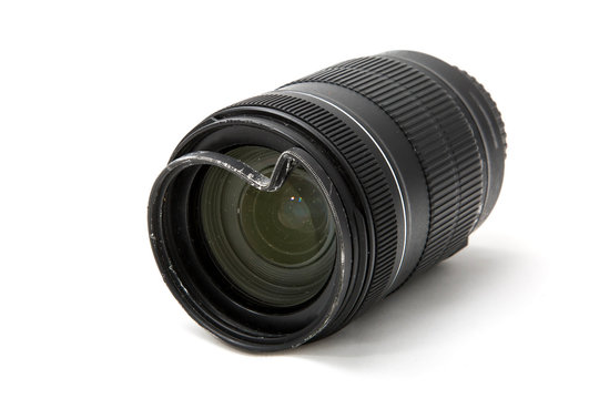 Damaged and broken zoom lens for the digital camera, dented protective UV filter. Front side view. To be repaired. Isolated on white background