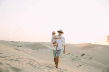 Father holding his little daughter in dress in the desert