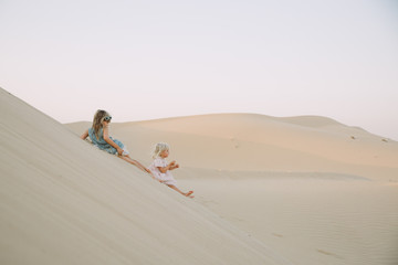 Two little girls sliding down the sand dune in Dubai