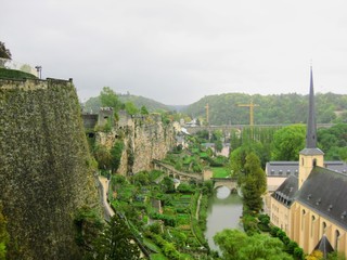 View of Luxembourg City with Alzette River passing through the Grund Quarter and Abbey de Neumunster. Typical houses with black slate roofs in Luxembourg City