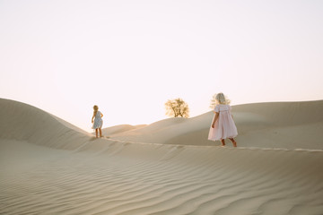 Two little girl walking on sand dunes in the desert in Dubai