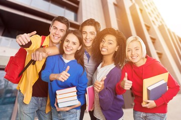 Group of Students with books gesturing thumbs