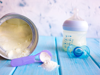 Composition with feeding bottle of baby milk formula on wooden table