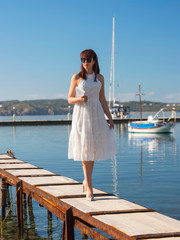 young woman walking with book in hand by pier in yacht club 