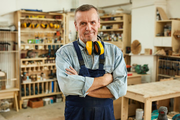 Waist up portrait of confident senior carpenter looking at camera while working in joinery, copy space