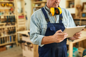 Mid section portrait of senior carpenter using tablet while working in joinery, copy space