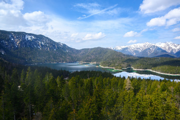 Aerial view of Eibsee against a blue sky with clouds, mountain lake near Garmisch Partenkirchen, bavarian Alps, Germany, copy space